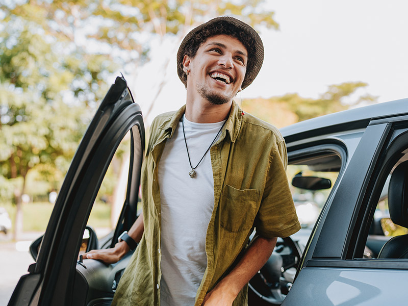 man smiling while getting out of his car