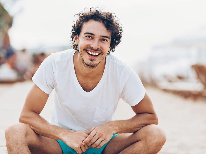 man smiling while sitting on the beach